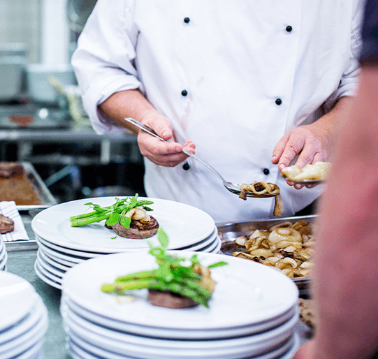 Chef scooping food onto dishes